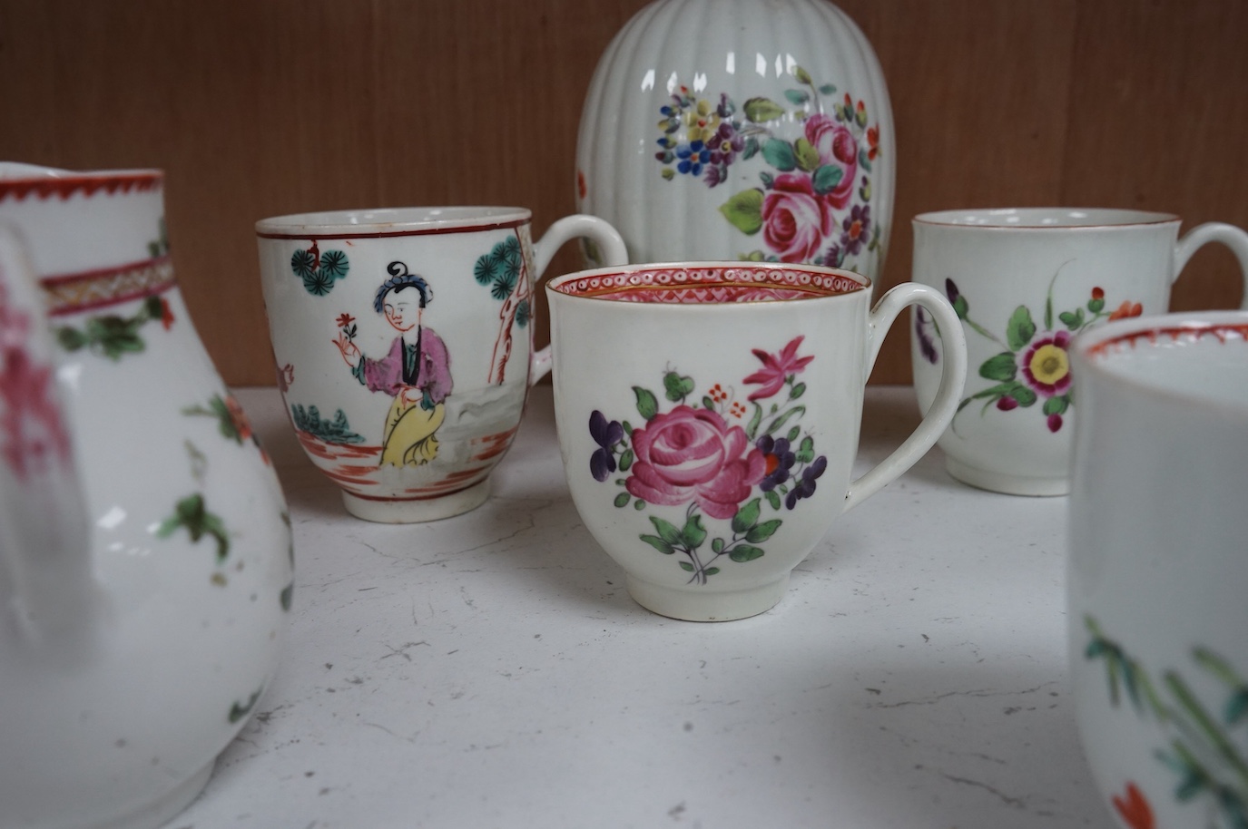 Worcester polychrome tea and coffee wares, c.1760-1780, comprising a tea caddy, a cream jug, five coffee cups and a fluted bowl, the latter with red anchor mark (8), largest tea caddy 14cm high.